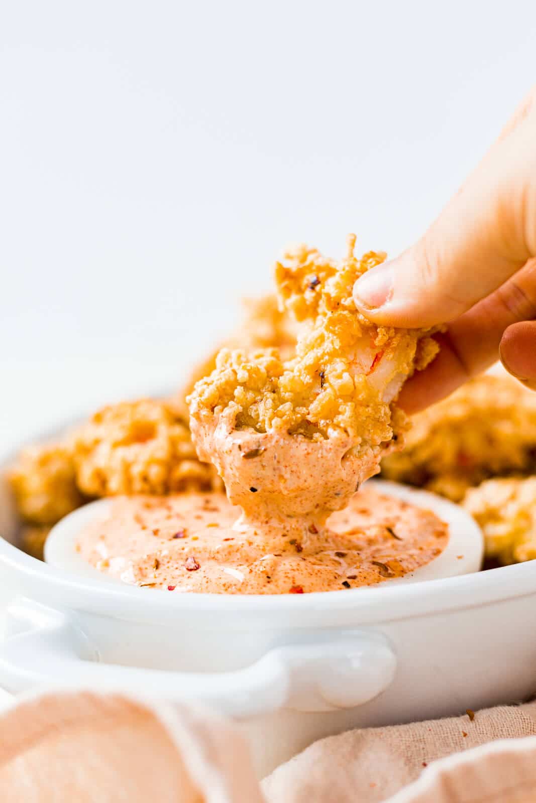 air fryer shrimp being dipped into a spicy remoulaude sauce