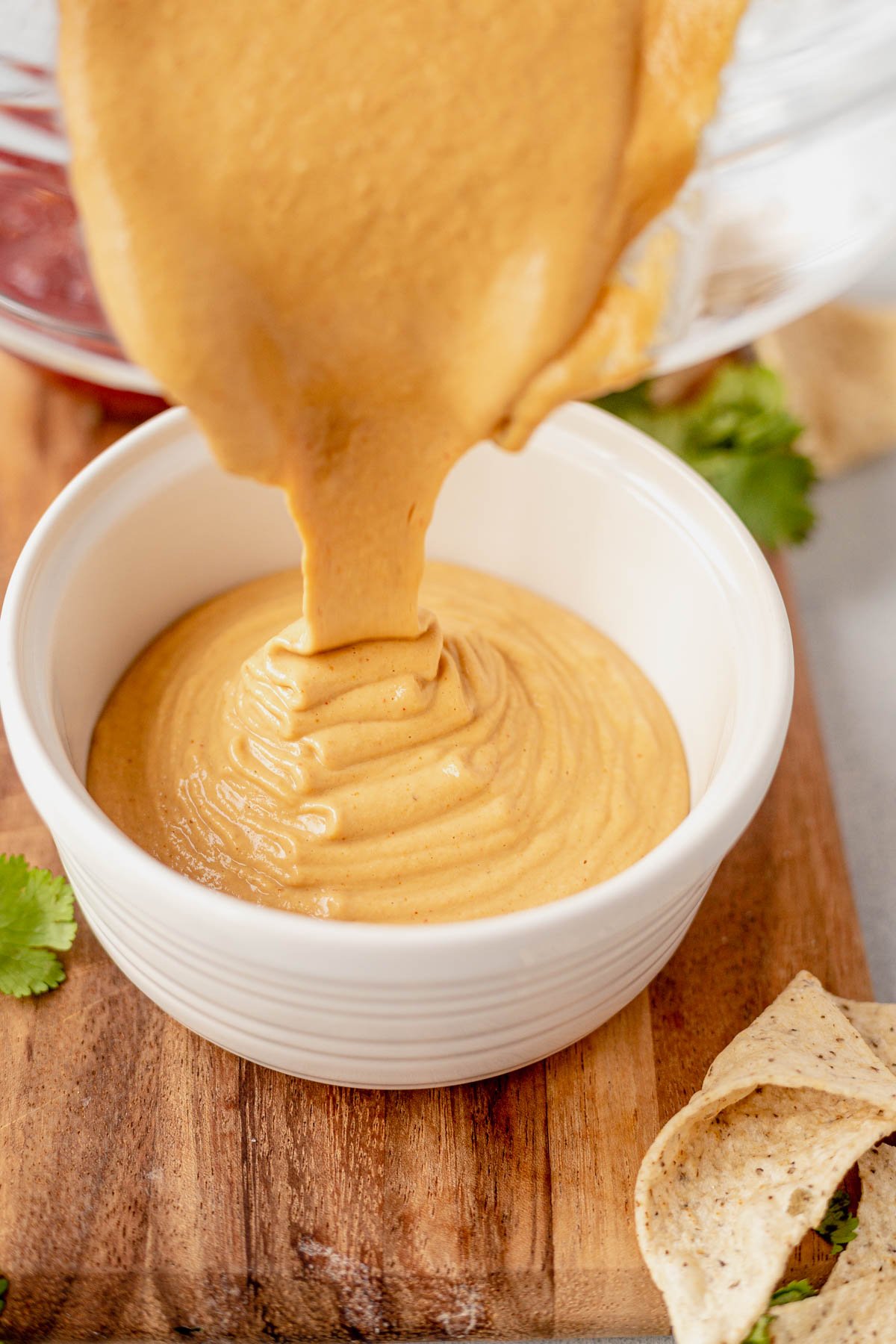 pouring cashew queso into a sauce cup