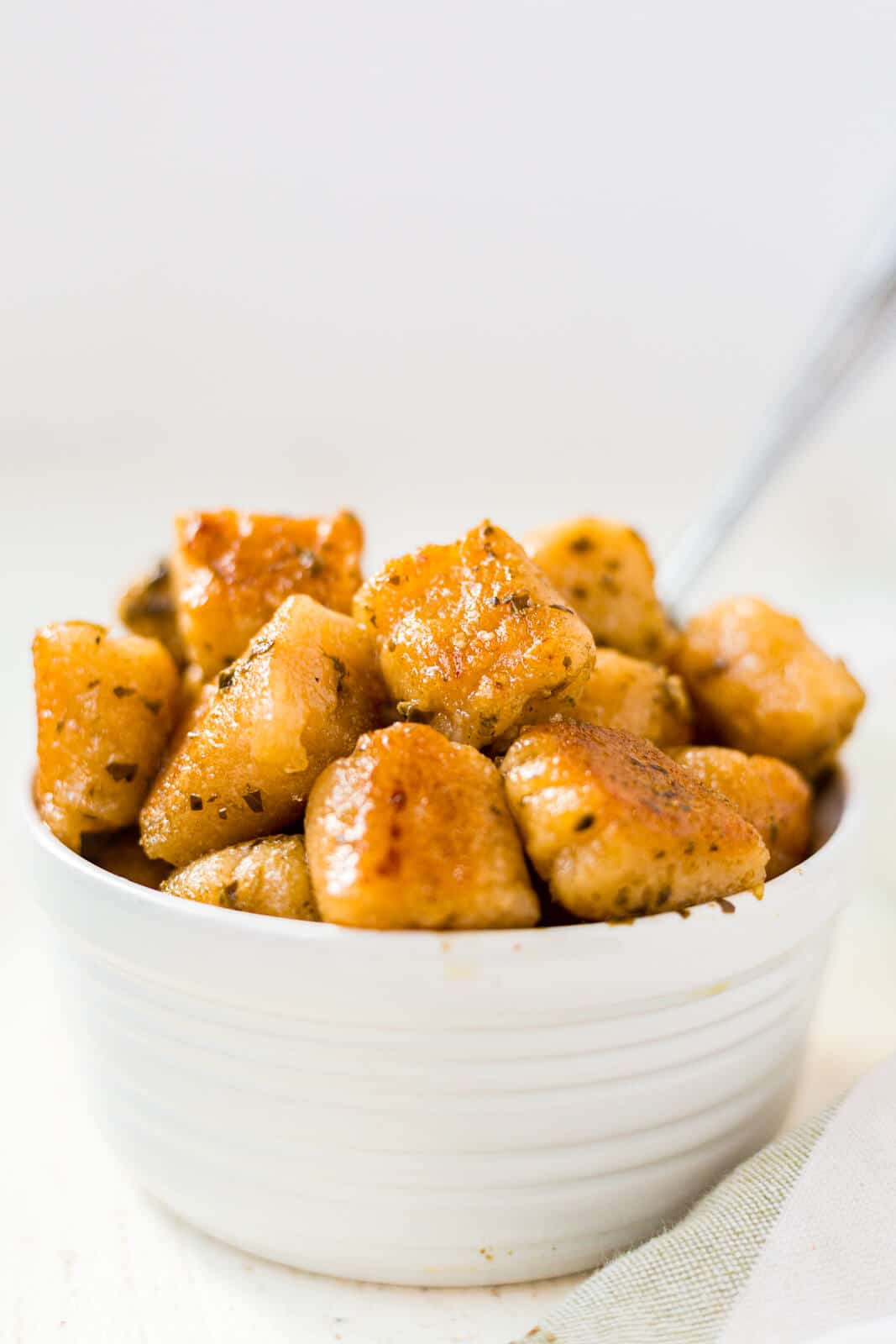 homemade cauliflower gnocchi in a white bowl tossed in basil pesto