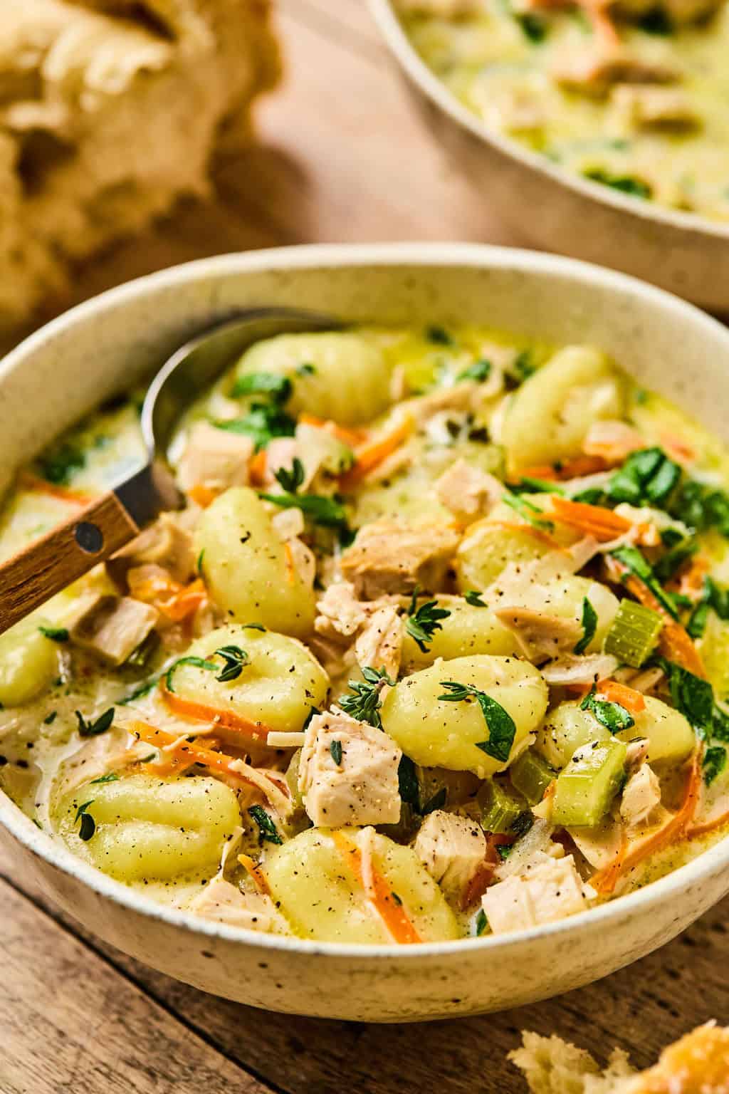 a bowl of chicken gnocchi soup with a spoon in it.