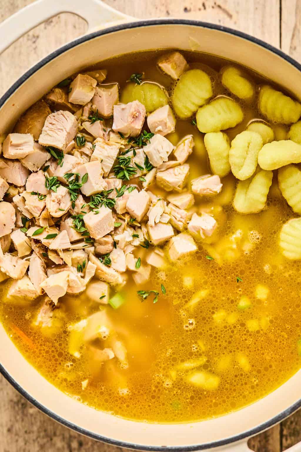 chicken and gnocchie in a pot of soup.