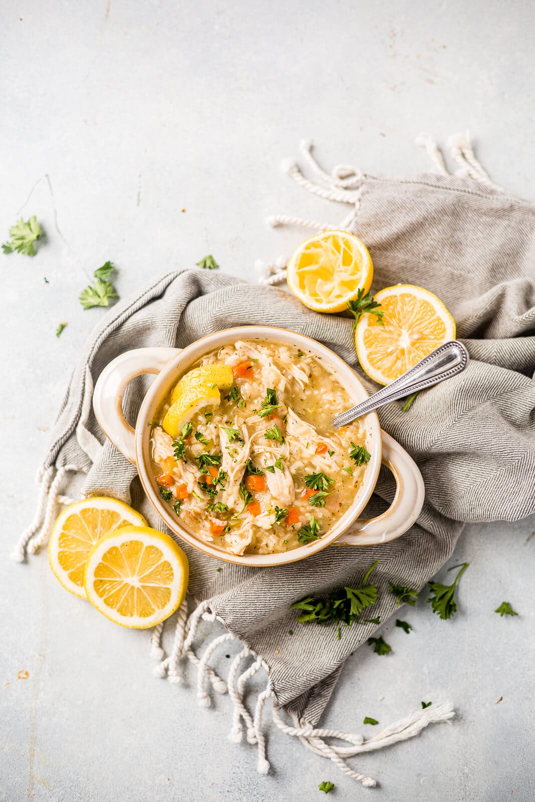 greek lemon chicken soup in a white bowl on a table garnished with lemon and parsley