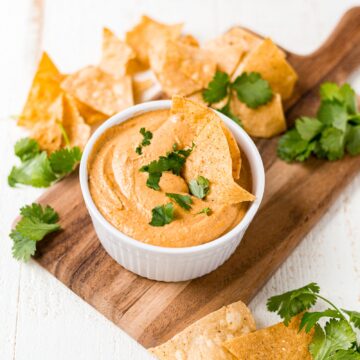 vegan cashew queso in a white dish topped with chopped cilantro
