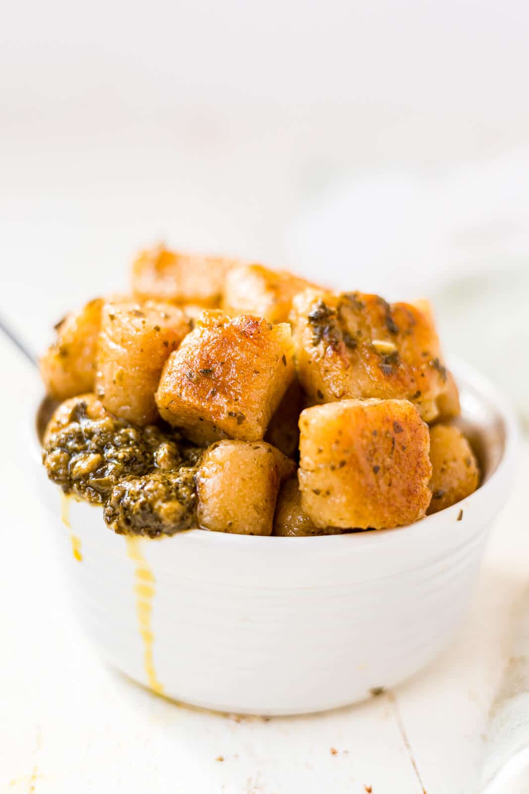 homemade cauliflower gnocchi piled into a white bowl tossed in pesto