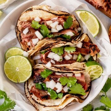 three authentic carne asada tacos on a plate with lime