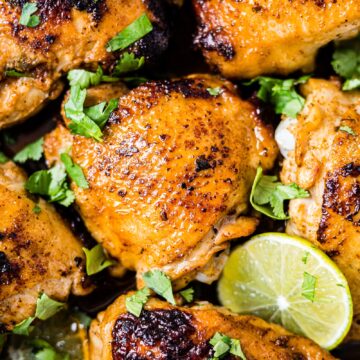crispy cilantro lime chicken in a oven safe pan with fresh cilantro and lime slices