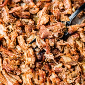 a black fork scooping out crispy instant pot carnitas from a sheet pan