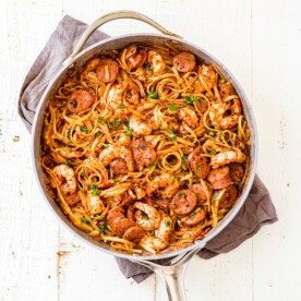 a large skillet filled with creamy cajun shrimp pasta topped with pasta