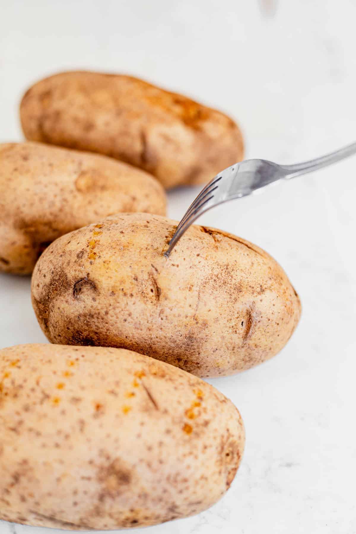 poking a russet potato with a fork.