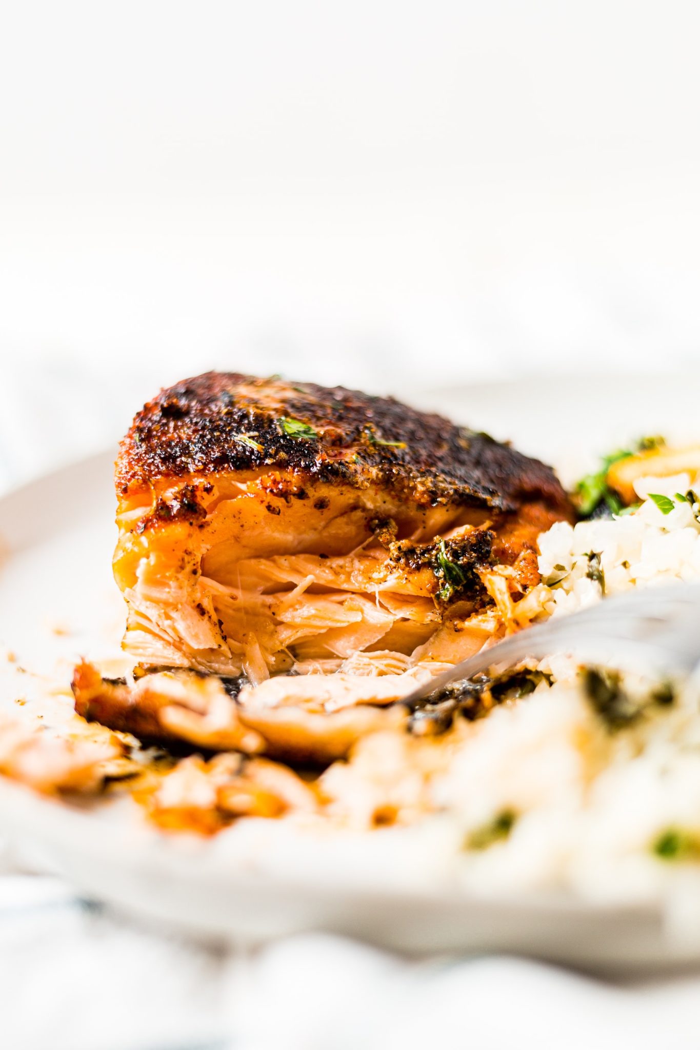 a piece of salmon on a plate with a bite taken out to see the flaky center