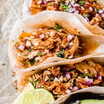 chicken tinga tacos topped with red onion, cilantro and lime juice
