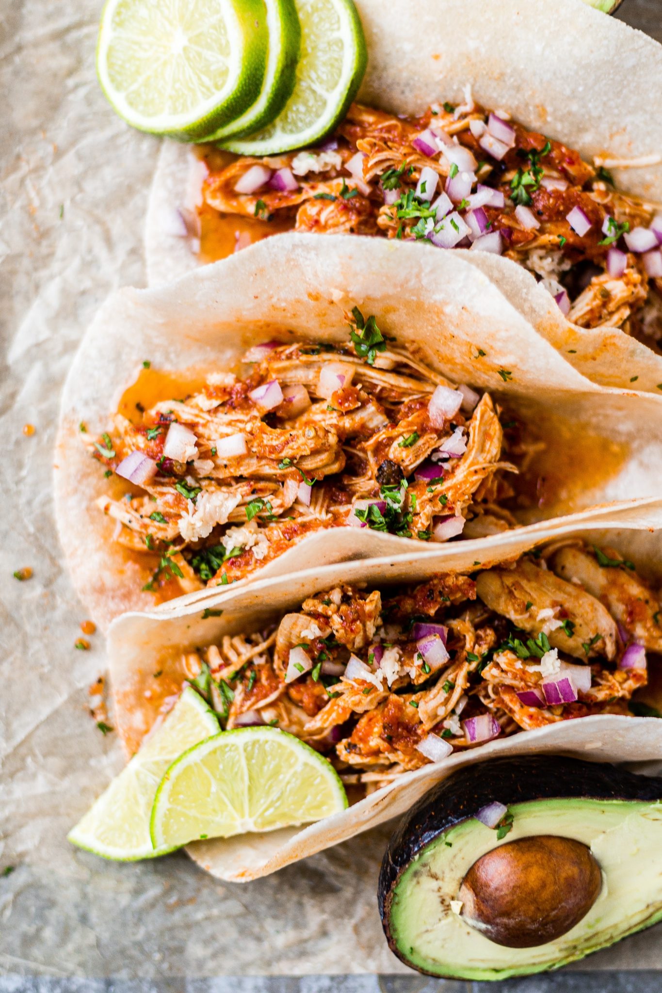 three tacos filled with chicken tinga from the instant pot and topped with fresh lime, onion and cilantro