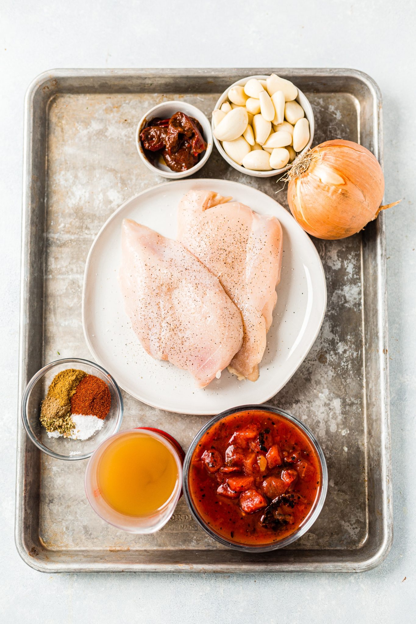 ingredients for chicken tinga arranged on a large sheet pan