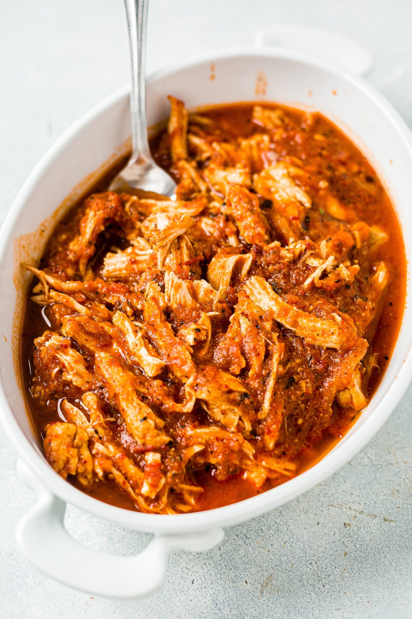chicken tinga in a white serving dish with a fork