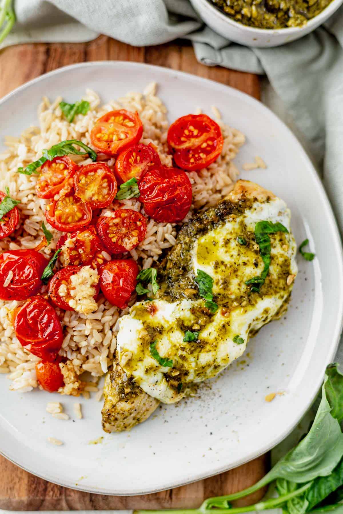 pesto chicken on a plate with rice and roasted tomatoes