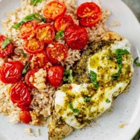 pesto chicken breast on a plate with brown rice and roasted tomatoes
