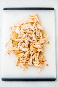 shredded chicken tinga on a white cutting board