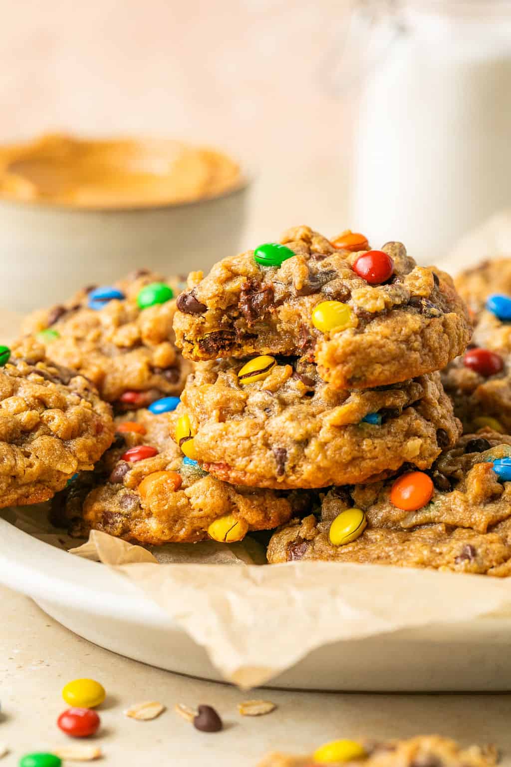 flourless monster cookies stacked on a plate with a bite missing from one