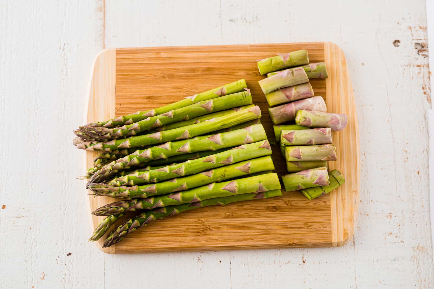 raw asparagus on a cutting board with the ends trimmed