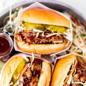 instant pot pulled pork sandwiches in a dish with bbq sauce and pickles