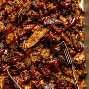 instant pot pulled pork drizzled with bbq sauce on a sheet pan.