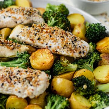 everything bagel chicken tenders on a bed of roasted broccoli and potatoes