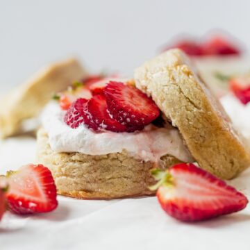 gluten free vegan strawberry shortcake on a piece of parchment paper surrounded by fresh strawberries