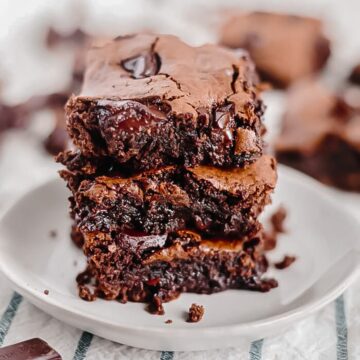 3 paleo brownies stacked on top of each other on a white plate