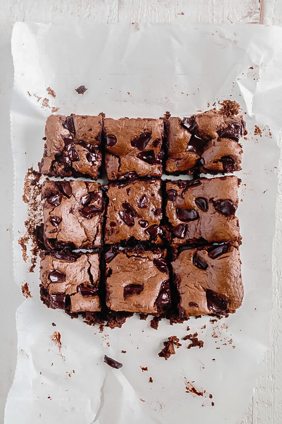 9 paleo brownies cut into large squares on a piece of parchment paper