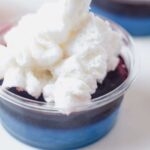 topping a red white and blue jello shot with whipped cream