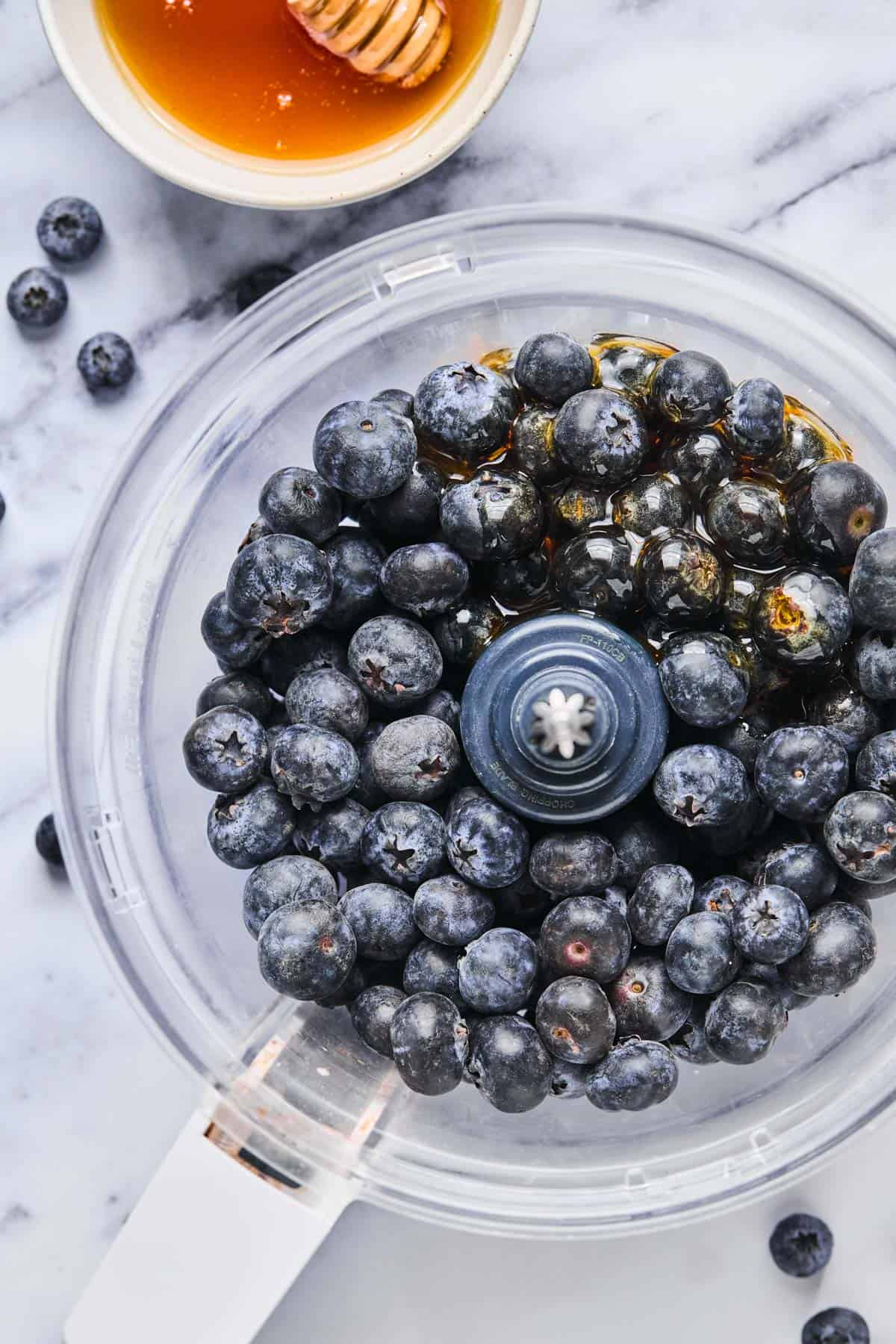 fresh blueberries and honey placed in a food processor