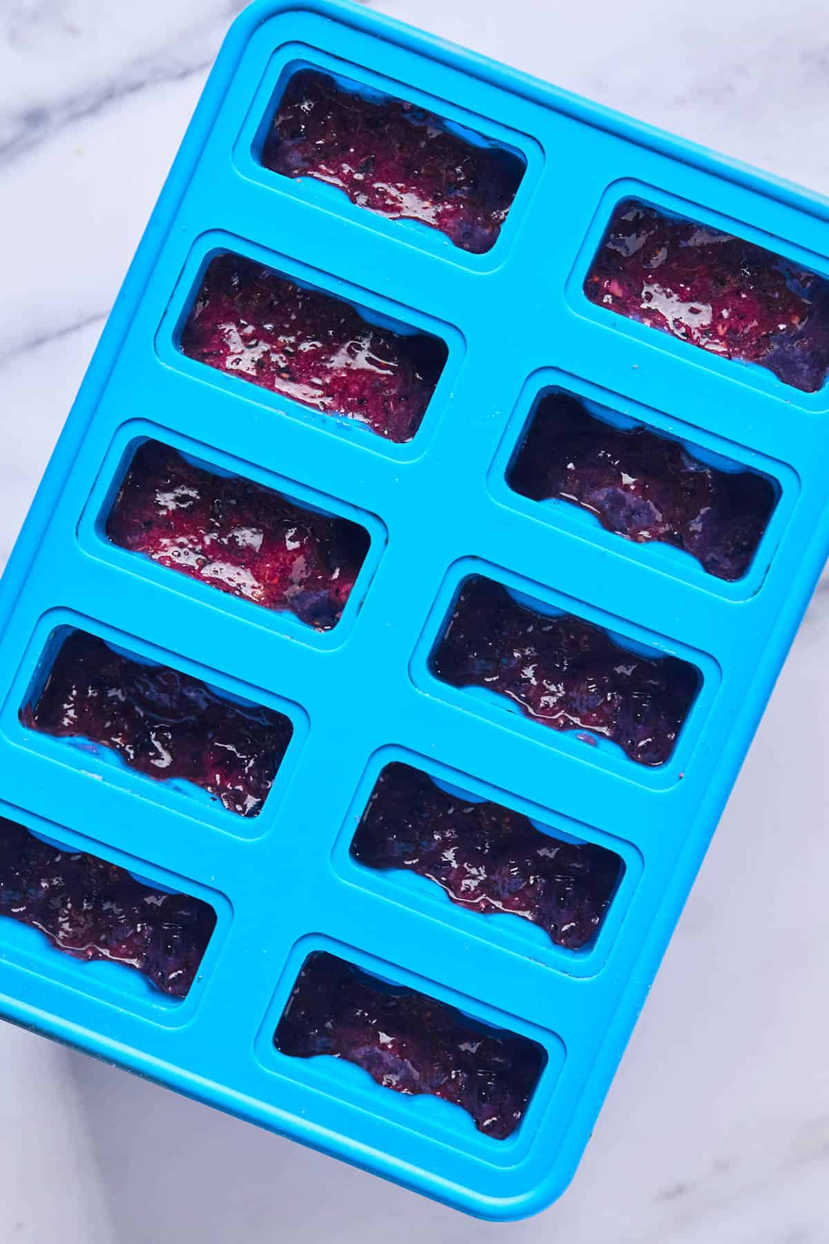 blueberry ice pop filling in popsicle mold stand
