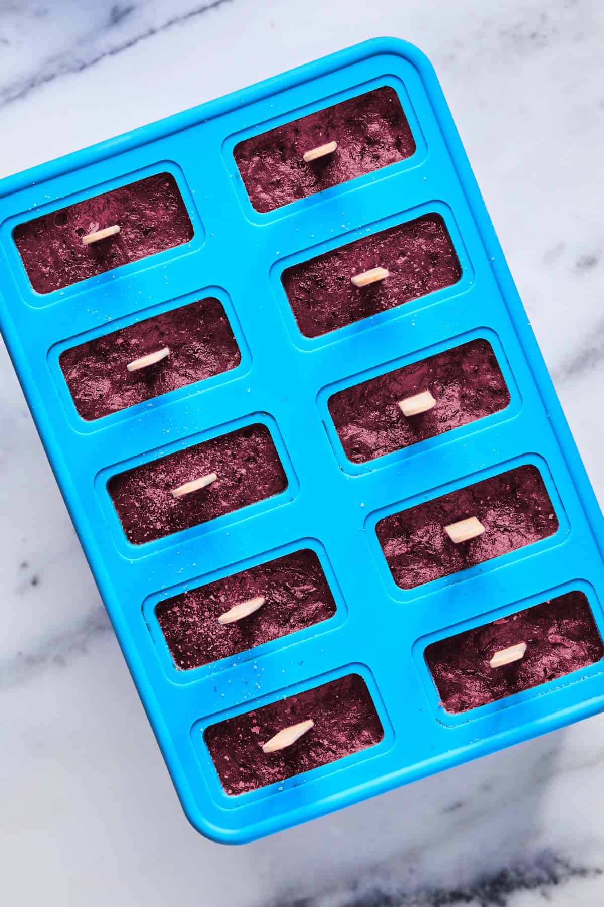 popsicle sticks in frozen blueberry ice pops frozen in popsicle mold