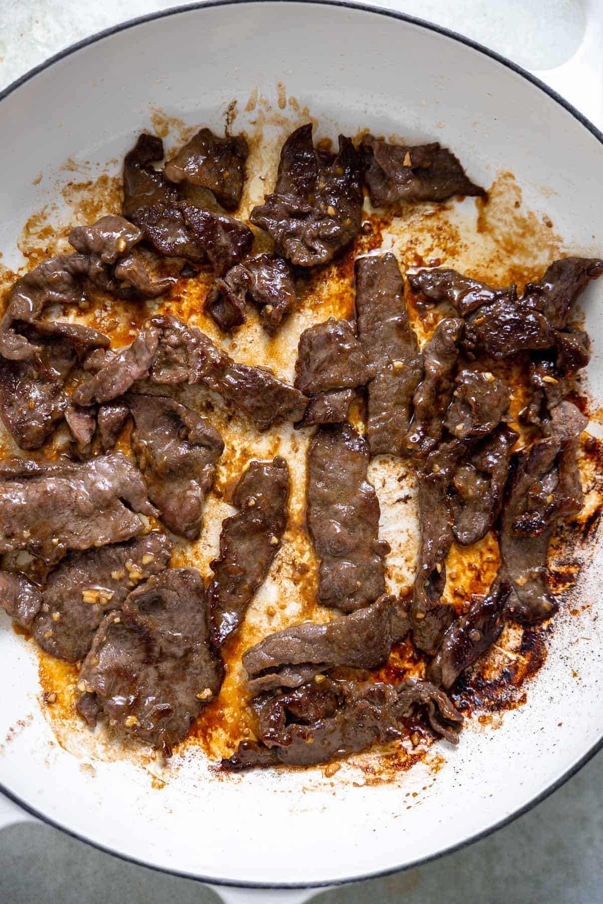 thinly sliced sirloin steak searing in a skillet.