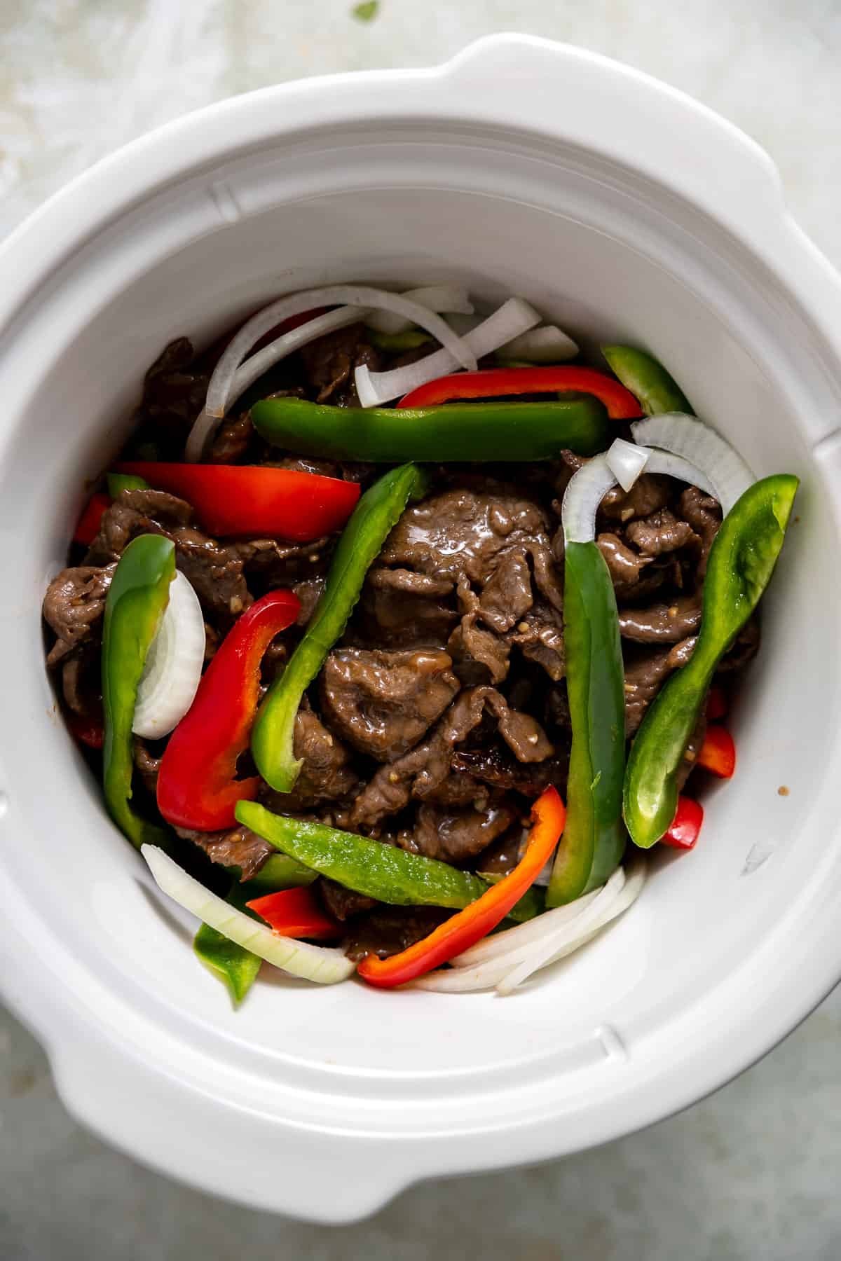 sirloin steak and peppers in a crock pot before cooking.