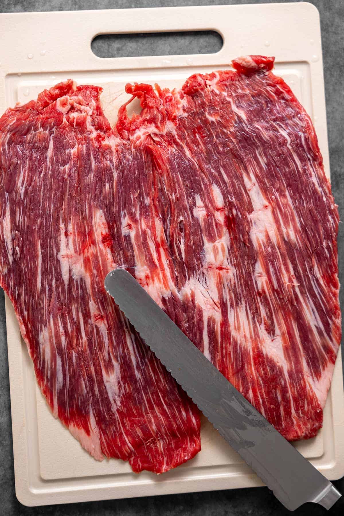 flank steak butterflied and laid flat on a cutting board.