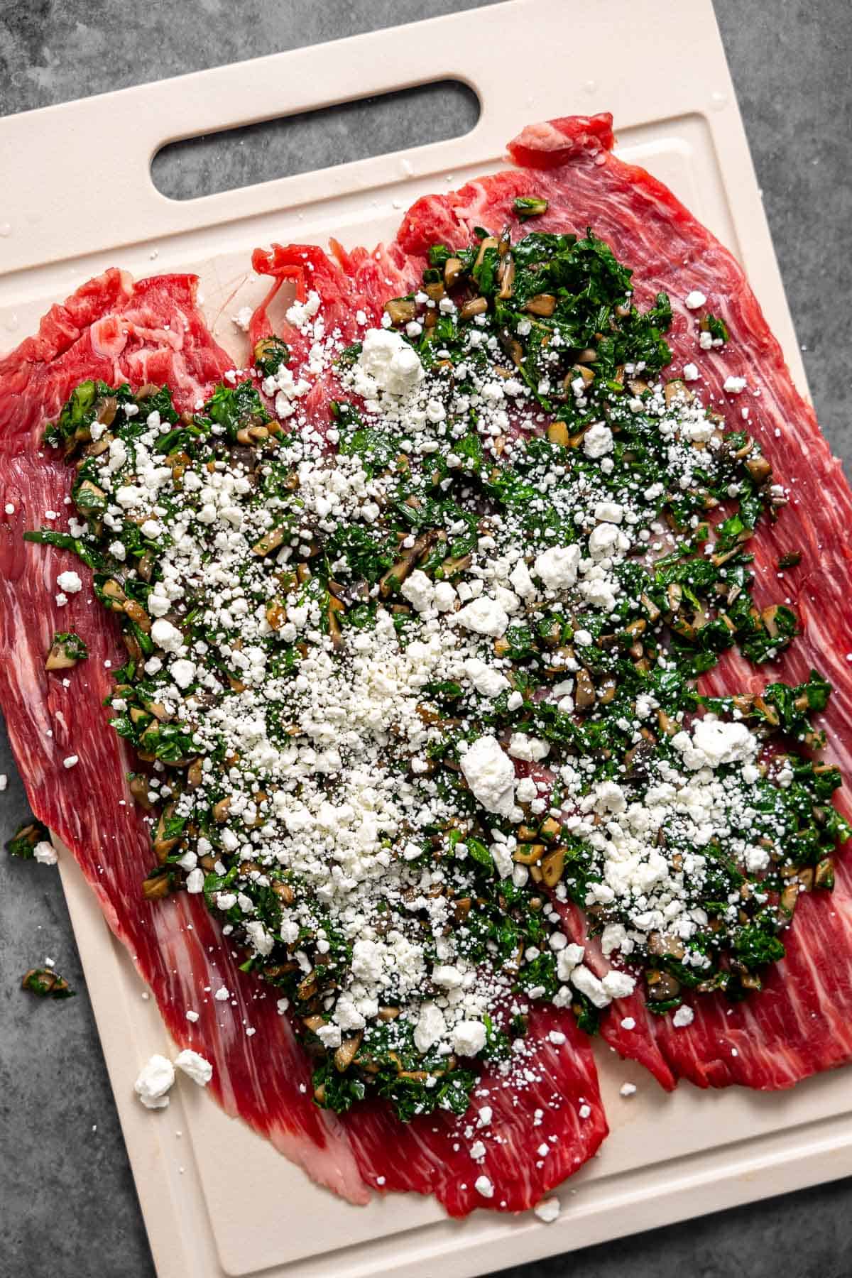 cooked mushroom, spinach, and goat cheese spread out on top of flank steak.