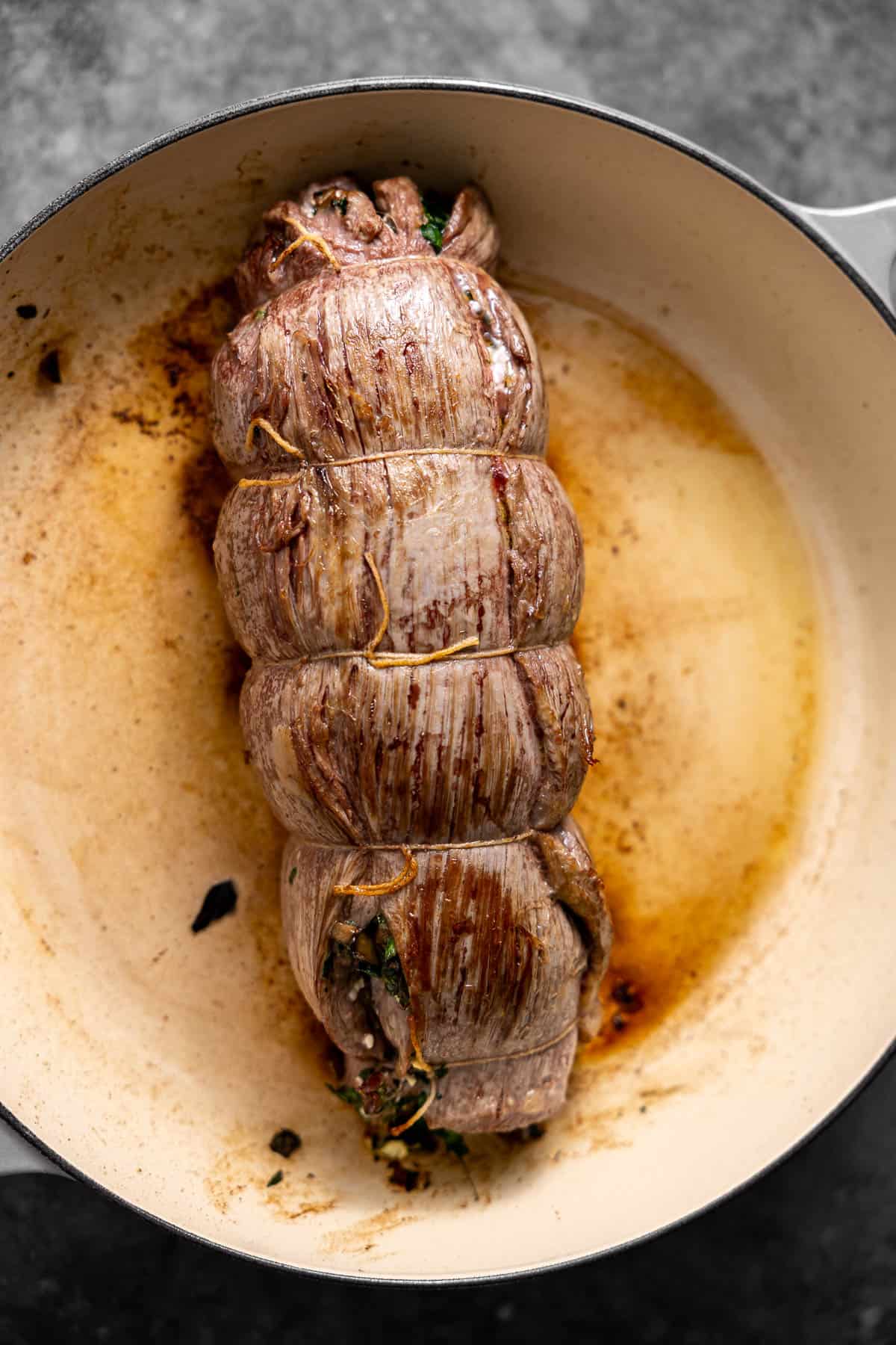 stuffed flank steak searing in a skillet.