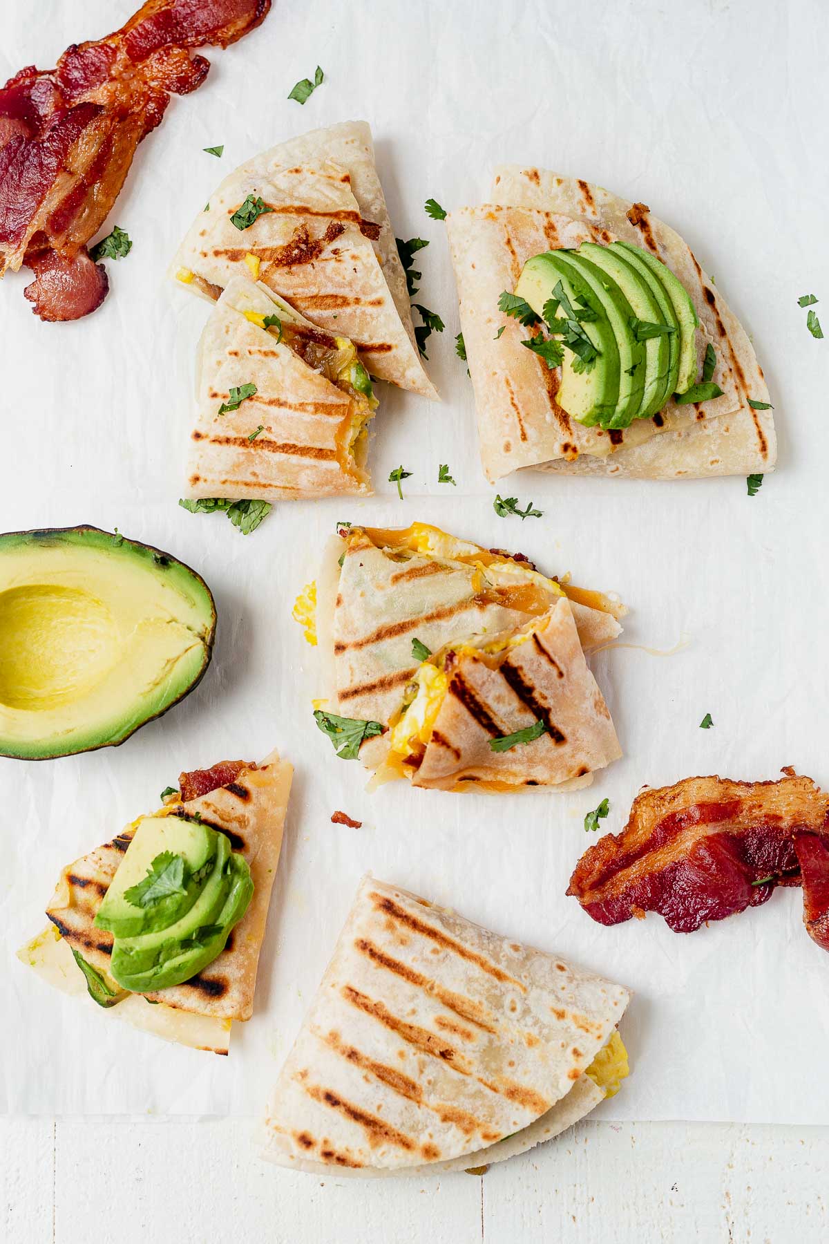 breakfast quesadillas with grill marks on parchment paper with bacon and avocado