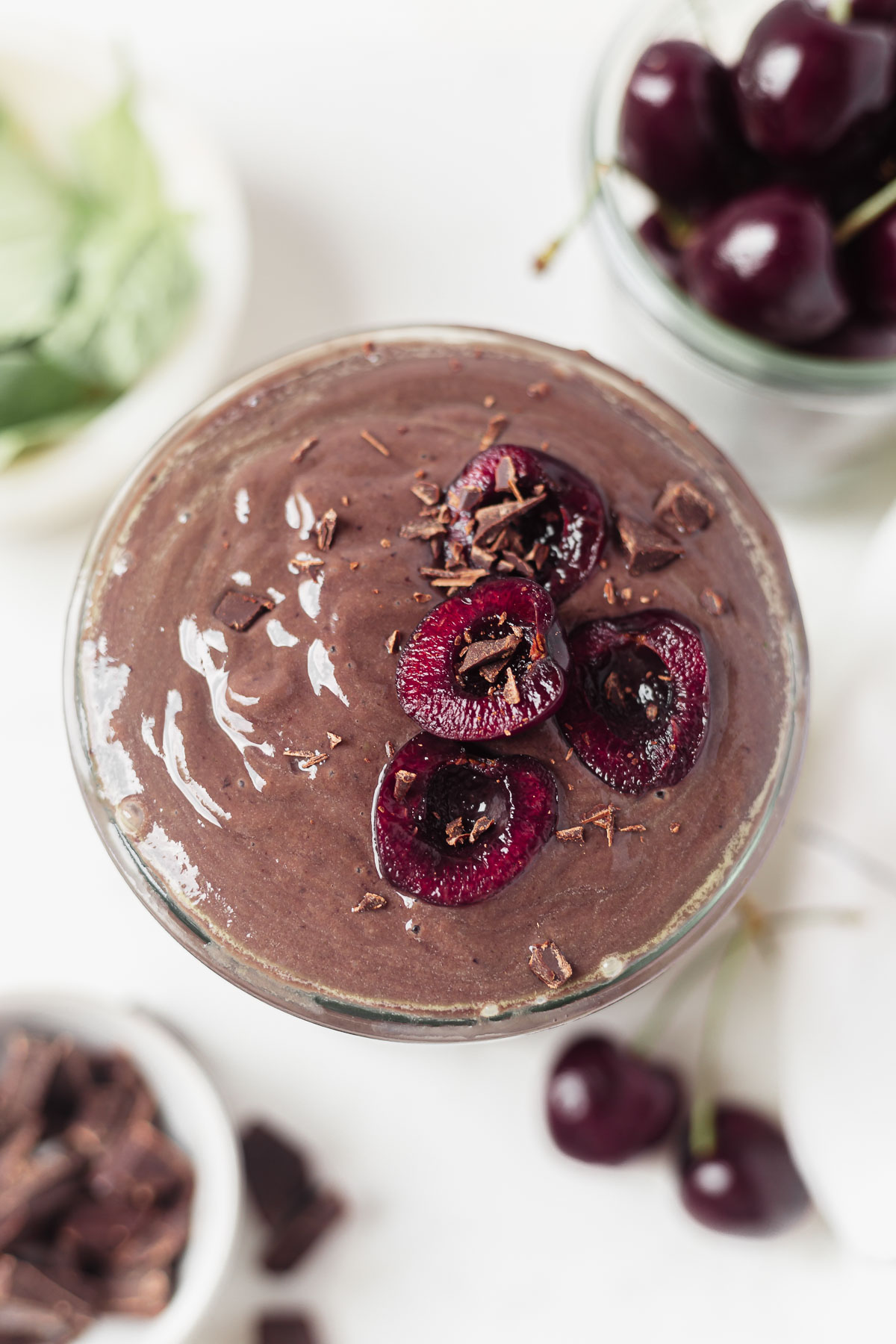 a glass filled with chocolate cherry smoothie and fresh cherries on top