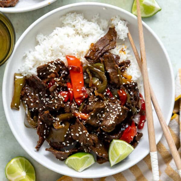 crock pot pepper steak in a bowl with rice and chopsticks.