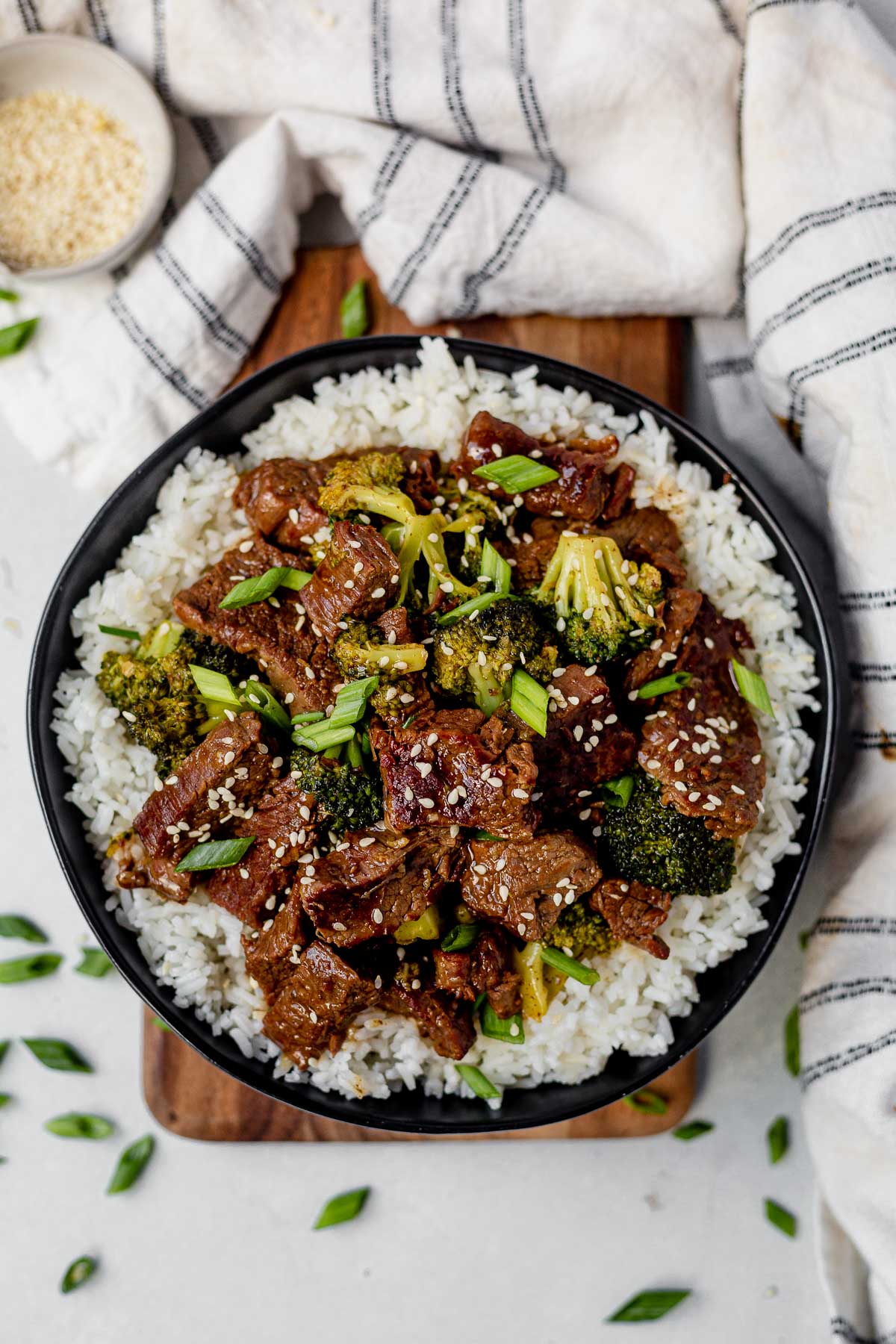 instant pot mongolian beef with broccoli in a black bowl with white rice and chopped green onion on top
