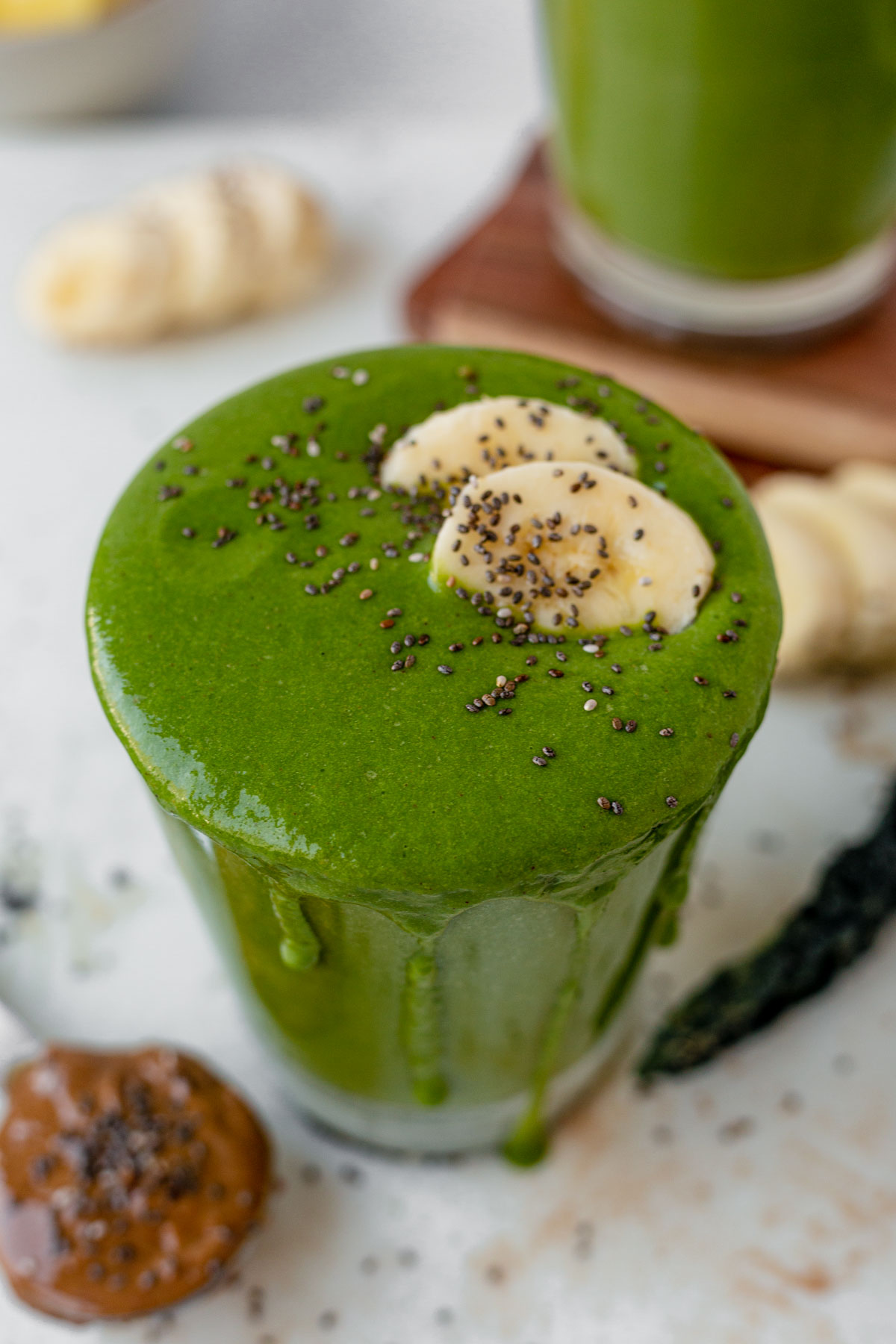 creamy tropical kale smoothie overflowing out of a glass