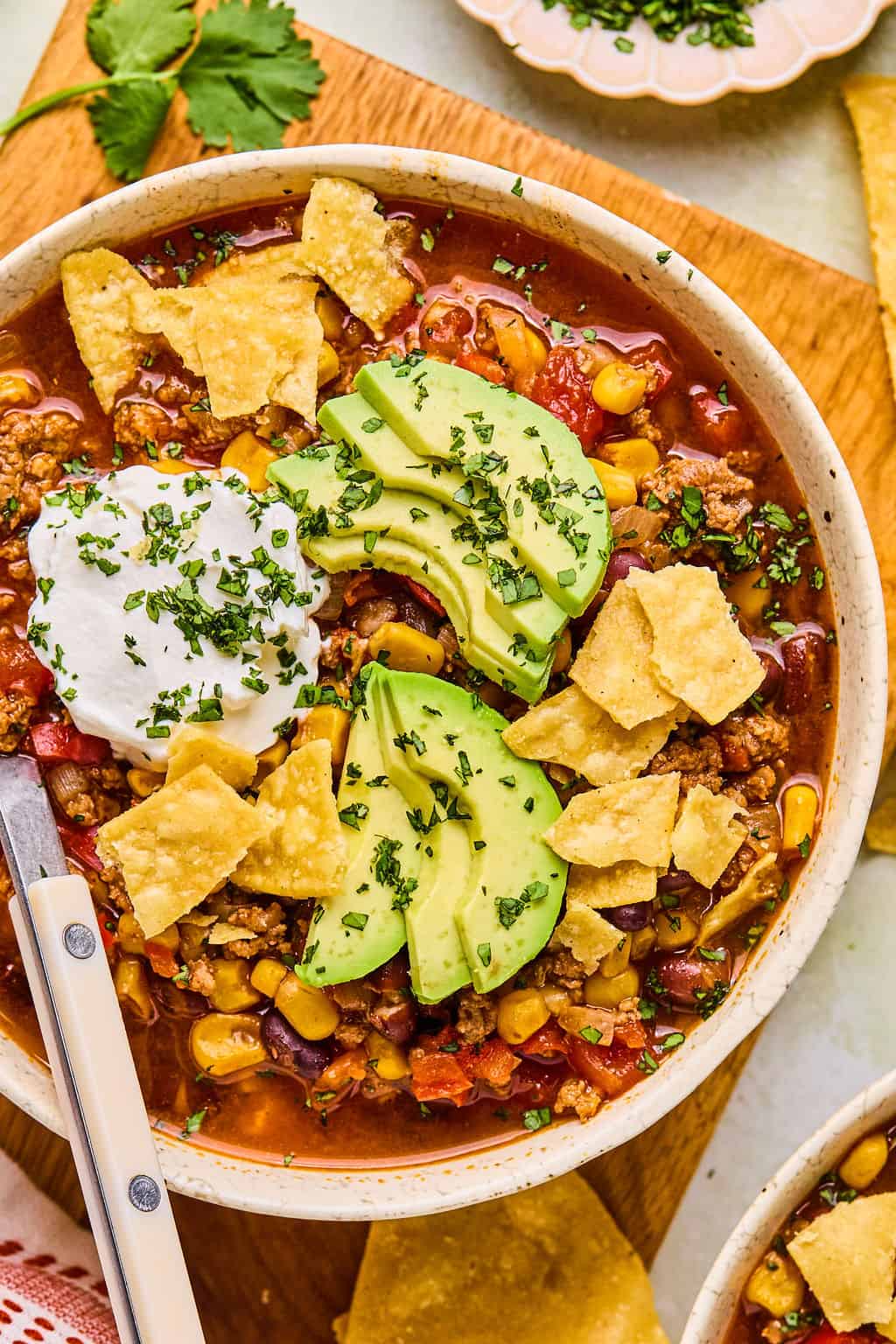 a bowl of instant pot taco soup topped with chips, avocado, and sour cream.