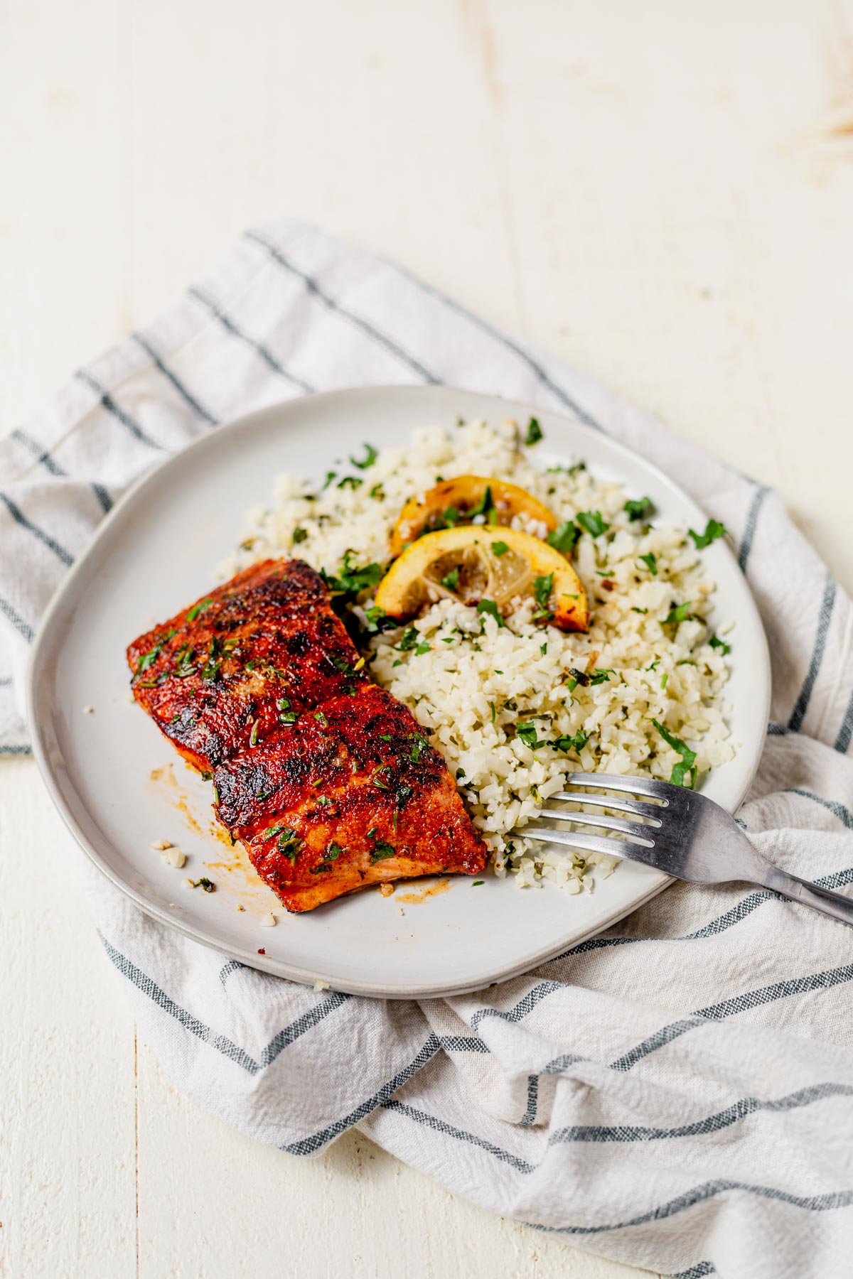 blackened salmon fillet on a plate with rice and parsley