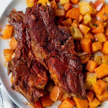 two instant pot country style ribs covered in bbq sauce on top of sweet potatoes