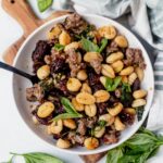 tuscan sausage sheet pan gnocchi served in a white bowl with fresh basil