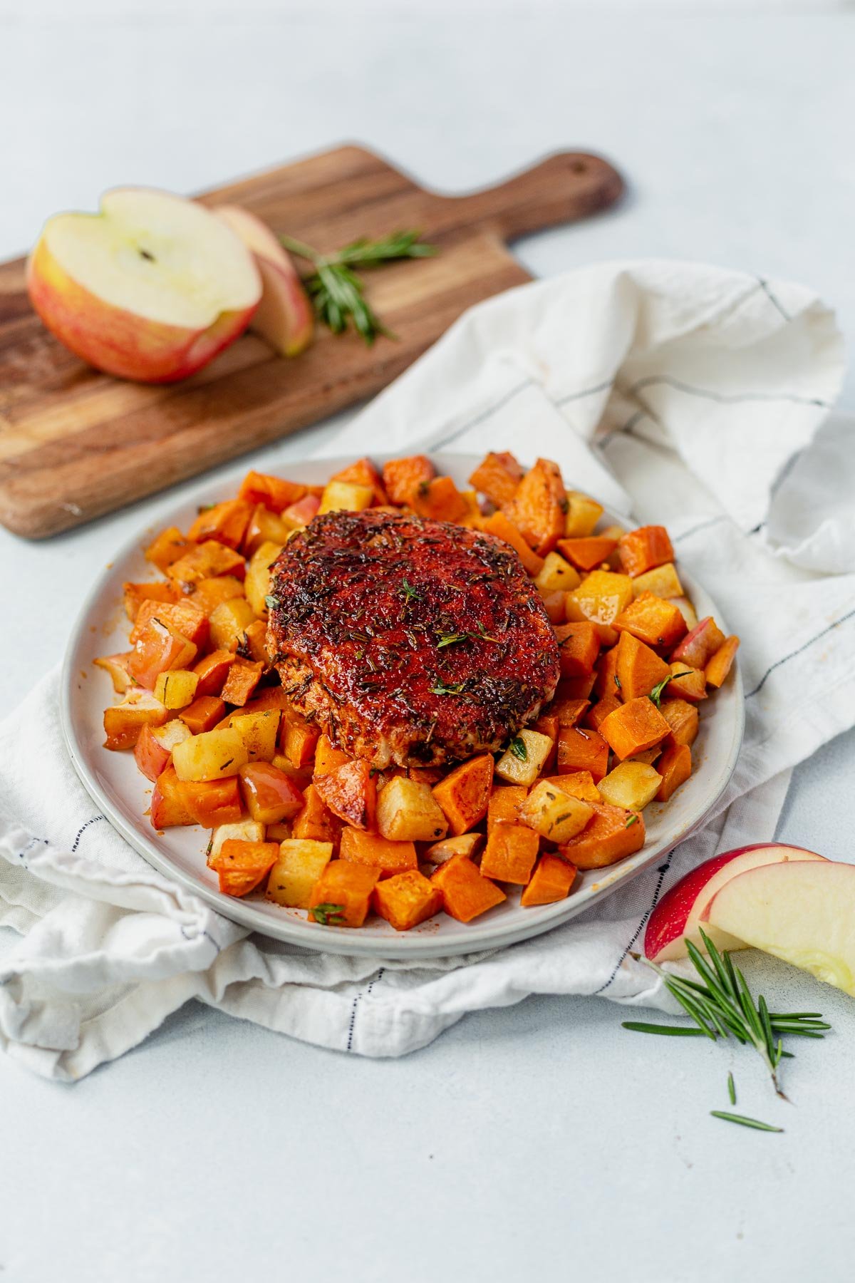 spice rubbed pork chops on a bed of sweet potatoes and apples 