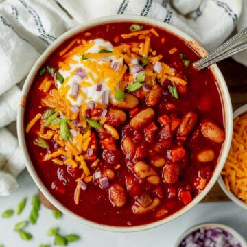 slow cooker vegetarian chili in a bowl topped with sour cream, cheese and onion