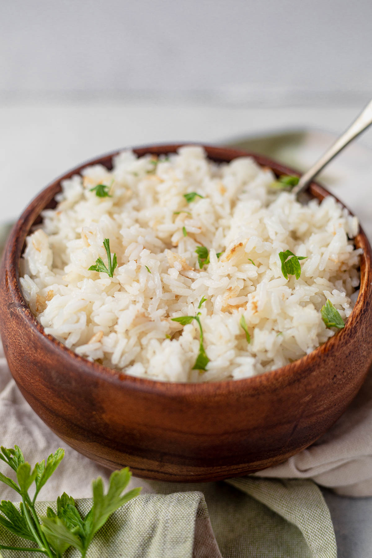 fluffy coconut rice in a wood bowl topped with fresh cilantro